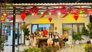 a group of people sitting at a table in front of a house at Ruby House beachfront Đồi Dương La Gi in Lagi