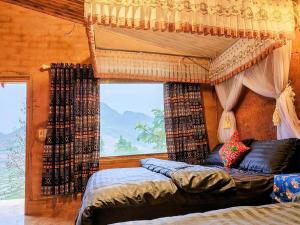 a bedroom with a canopy bed and a window at LÝ GIA HOMESTAY in Ha Giang