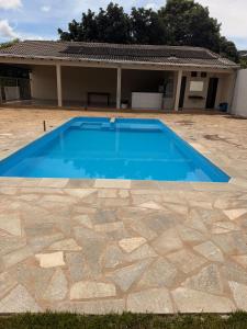 a blue swimming pool in front of a house at Recanto do boto in Anápolis