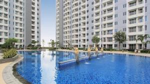 a large swimming pool in front of two large buildings at Tanglin Tower with Netfix by AquHome in Surabaya