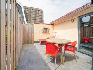 a patio with a table and red chairs at Callantsoog Group getaway Beach in Callantsoog