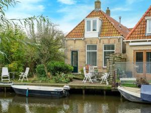 a house on the water with a boat in front at Waterside stay with Private Jetty in Heeg