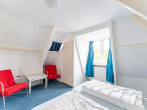 a bedroom with a bed and two red chairs at Waterside stay with Private Jetty in Heeg
