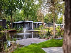 a park with a pond and a building with a fountain at Nature Park Chalet in Hoenderloo in Hoenderloo