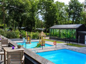 a backyard swimming pool with a playground and a gazebo at Nature Park Chalet in Hoenderloo in Hoenderloo