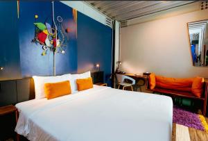a bedroom with a large white bed with orange pillows at MeStyle Garage Hotel in Bangkok