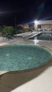a large swimming pool at night with a light at Refúgio com estilo 2 Quartos 6 Pessoas in Bertioga