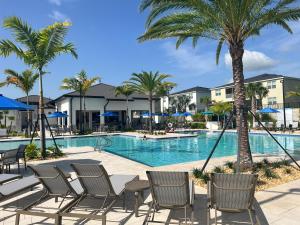 a swimming pool with chairs and palm trees at Resort Style, close to Disney and other parks in Davenport