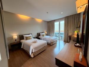 ein Hotelzimmer mit zwei Betten und einem Fernseher in der Unterkunft Le Patta Resort & Hotel Chiang Rai in Chiang Rai