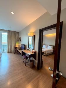 ein Hotelzimmer mit Bett, Schreibtisch und Spiegel in der Unterkunft Le Patta Resort & Hotel Chiang Rai in Chiang Rai