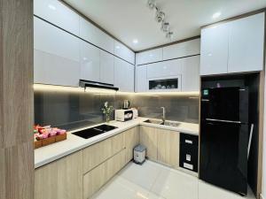 a kitchen with white cabinets and a black refrigerator at AC Nera Garden Apartment in Thôn Văn Dương
