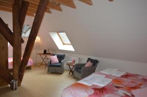 een slaapkamer met een bed en stoelen op een zolder bij B&B Idylle aan Zee incl 2 Wellnessstudios in Sint Maartensvlotbrug