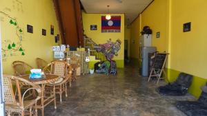 a room with a table and chairs and a yellow wall at Pakse Chill Hostel in Pakse
