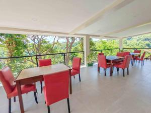 a dining room with red chairs and tables on a balcony at Caliraya Music Camp in Cavinti
