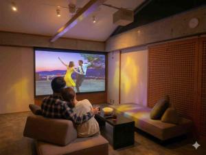 a man and a woman sitting in a living room watching a movie at スターハウス in Otsu