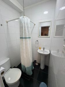 a white bathroom with a toilet and a sink at Raymi House Hostel in Arica +64 photos