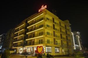 a large yellow building with a neon sign on it at Aither in Digha
