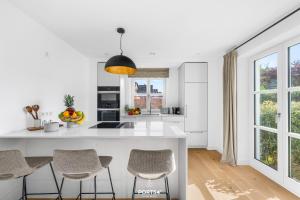 a kitchen with a white counter and some chairs at Villa Tinnum Sylt in Tinnum +37 photos