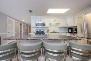 a kitchen with a large counter with chairs around it at Phoenix X 506 condo in Orange Beach