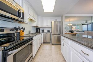 a kitchen with white cabinets and a stainless steel refrigerator at Phoenix X 506 condo in Orange Beach