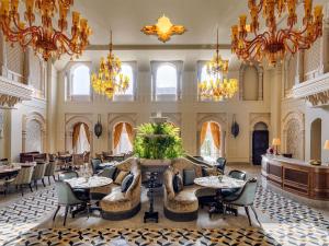 a hotel lobby with tables and chairs and chandeliers at Raffles Jaipur in Jaipur