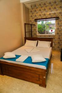 a bed with two pillows and a window in a room at Risha villa in Trincomalee