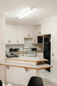 a kitchen with white cabinets and a black refrigerator at Unit 2, Rocky CBD in Rockhampton