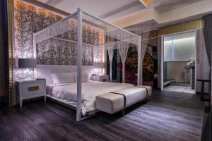 a bedroom with a white canopy bed and a bathroom at AmanCity Motel in Pingtung City
