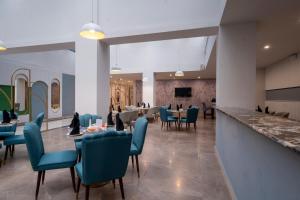 a restaurant with blue chairs and tables at Hotel One Gujranwala in Kot Mergulla