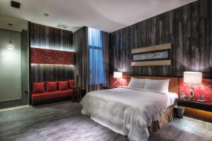 a bedroom with a large bed and a red couch at AmanCity Motel in Pingtung City