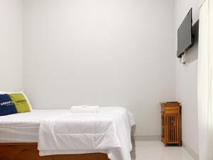 a white bedroom with a bed and a tv at Urbanview Hotel The Corner Pandowo in Ngaglik +38 photos