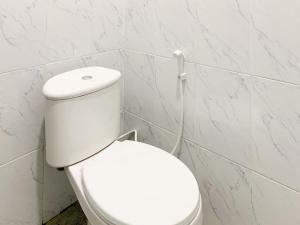 a white toilet in a white tiled bathroom at Urbanview Hotel The Corner Pandowo in Ngaglik