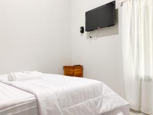 a white bedroom with a bed and a flat screen tv at Urbanview Hotel The Corner Pandowo in Ngaglik