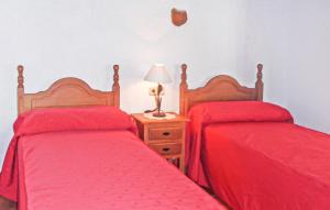 two beds in a bedroom with red sheets and a lamp at La Casa Grande in Málaga