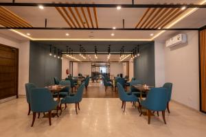a dining room with tables and blue chairs at Hotel One Gujranwala in Kot Mergulla