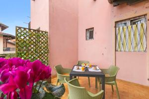a table and chairs on a patio with purple flowers at Petalo Bianco: 100m from Lake, Parking and Balcony - Happy Rentals in Baveno +15 photos