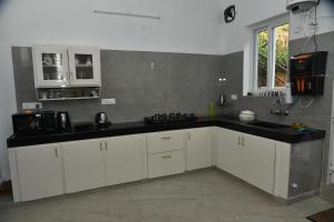a kitchen with white cabinets and a black counter top at Shans Valley in Kotagiri