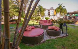a group of chairs with red pillows in a park at Life Resort - Flat Aconchegante in Brasília