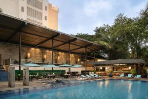 a hotel with a pool and tables and chairs at Grand Mercure Bangalore - An Accor Brand in Bangalore