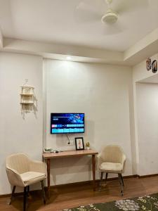 a room with a desk with two chairs and a tv at Comfort Corner in Greater Noida