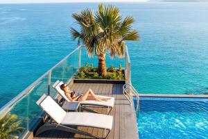 a woman sitting in a chair next to a swimming pool at Boton Blue Hotel & Spa in Nha Trang