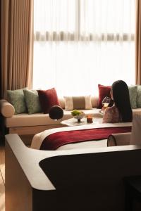 a woman sitting on a bed in a room at The Auberg Collection Hotel in Ho Chi Minh City