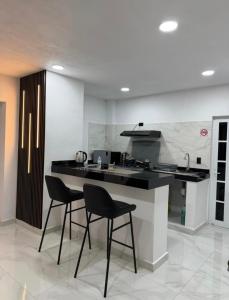 a kitchen with two black chairs and a counter at Casa Azteca de Oro in San Sebastian Xolalpa
