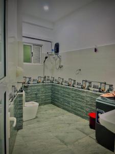 a bathroom with a green tiled wall with a tub and sinks at Akarsha Residence - Near Airport in Negombo