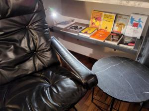 a leather chair in front of a table with books at Le Cœur Urban Suite Parma in Parma