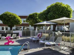a pool with chairs and umbrellas next to a building at Novotel Lyon Bron in Bron