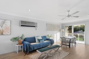a living room with a blue couch and a table at River Retreat in Dora Creek
