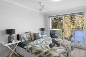 a bedroom with a bed and a large window at River Retreat in Dora Creek