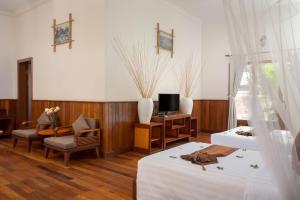 a bedroom with two beds and a desk and a tv at La Rivière d' Angkor Resort in Siem Reap