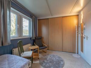 a bedroom with a bed and a chair and a window at Holiday Home near Dutch Beach with Pool in Sint Maartensvlotbrug